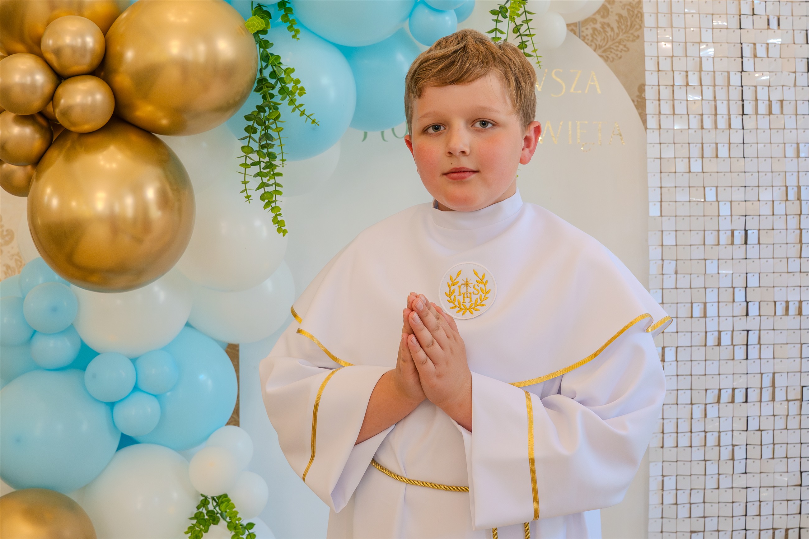 Portret dziecka przy dekoracji komunijnej podczas rodzinnego przyjęcia.